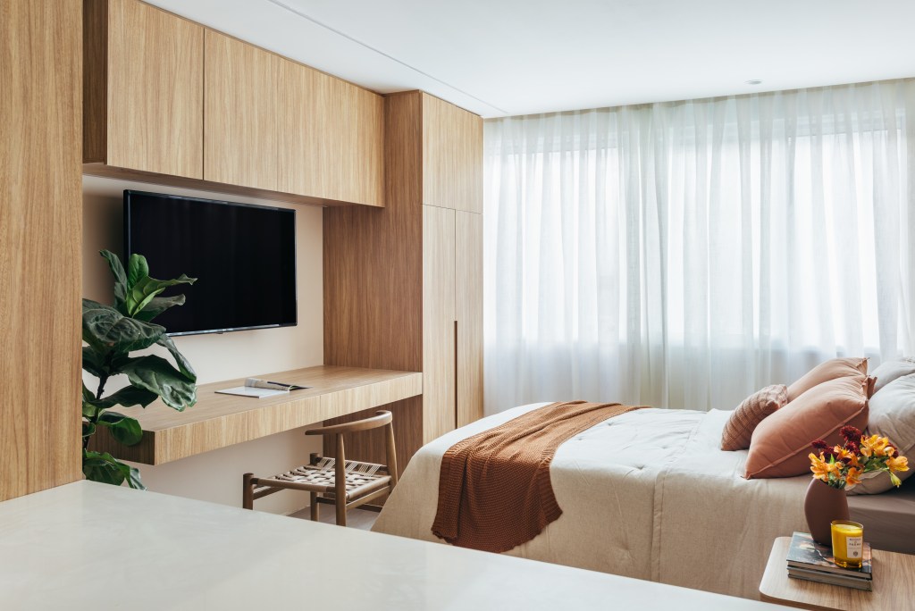 Micro apê de 25 m² tem cabeceira de azulejos e cozinha integrada ao quarto. Projeto de Rodolfo Consoli. Na foto, quarto com Tv e home office.