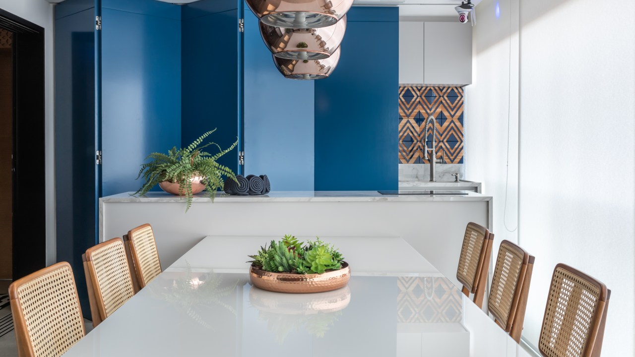 Painel retrátil esconde a churrasqueira neste apê descolado de 120 m². Projeto de Beatriz Quinelato. Na foto, varanda gourmet com painel azul que esconde a churrasqueira.