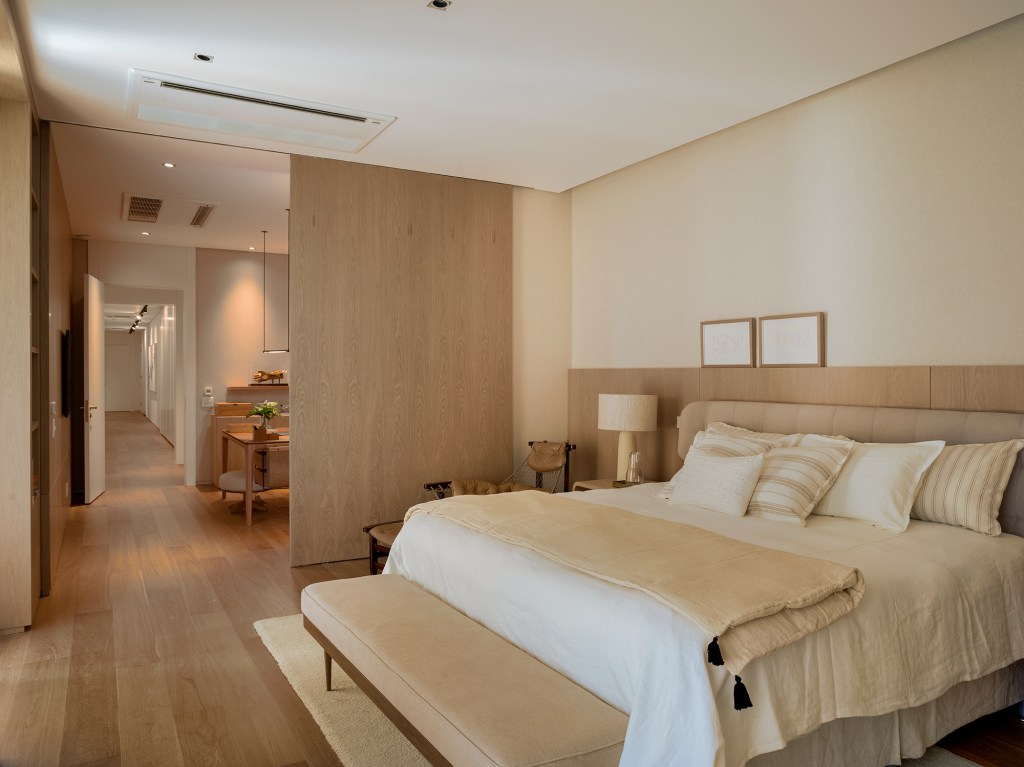Paola Ribeiro assina apartamento de 810 m² repleto de arte. Na foto, quarto de casal com parede de madeira.