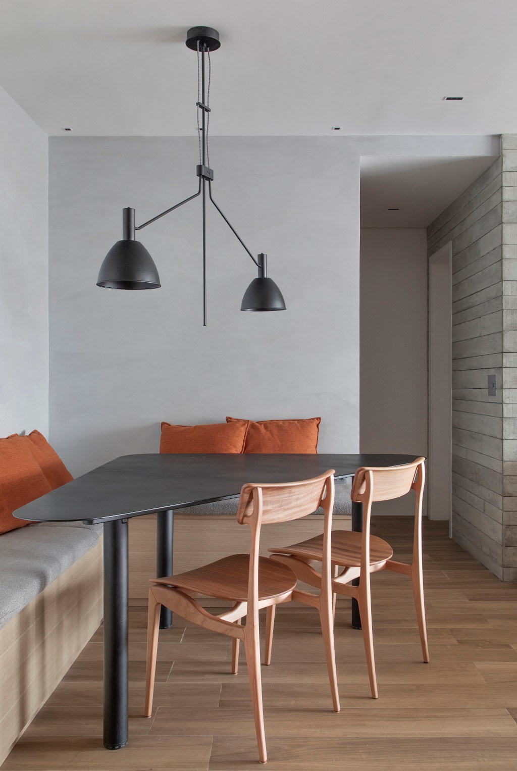 Preto e terracota marcam o décor deste apartamento masculino de 110 m². Projeto de Up3 Arquitetura. Na foto, sala de jantar com mesa triangular e canto alemão.