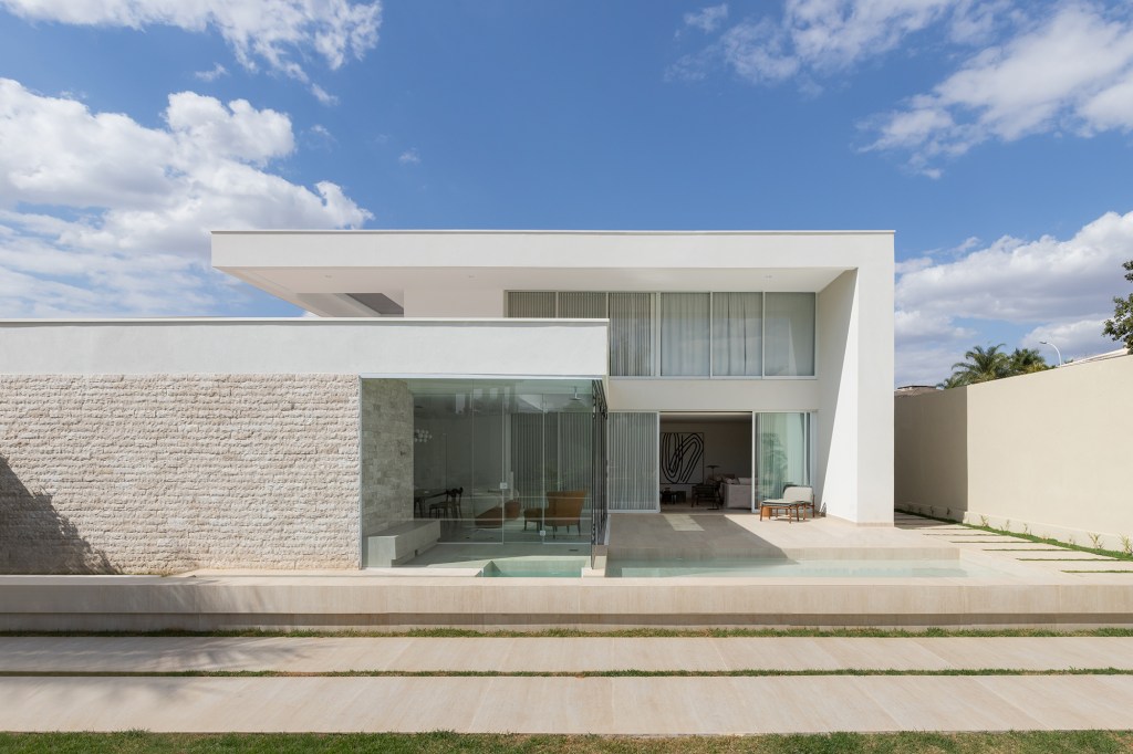 Adega e escada helicoidal se destacam em casa com projeto atemporal. Projeto Traama Arquitetura. Na foto, fachada da casa com piscina.