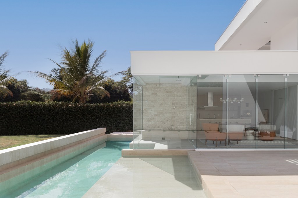 Adega e escada helicoidal se destacam em casa com projeto atemporal. Projeto Traama Arquitetura. Na foto, fachada da casa com piscina.
