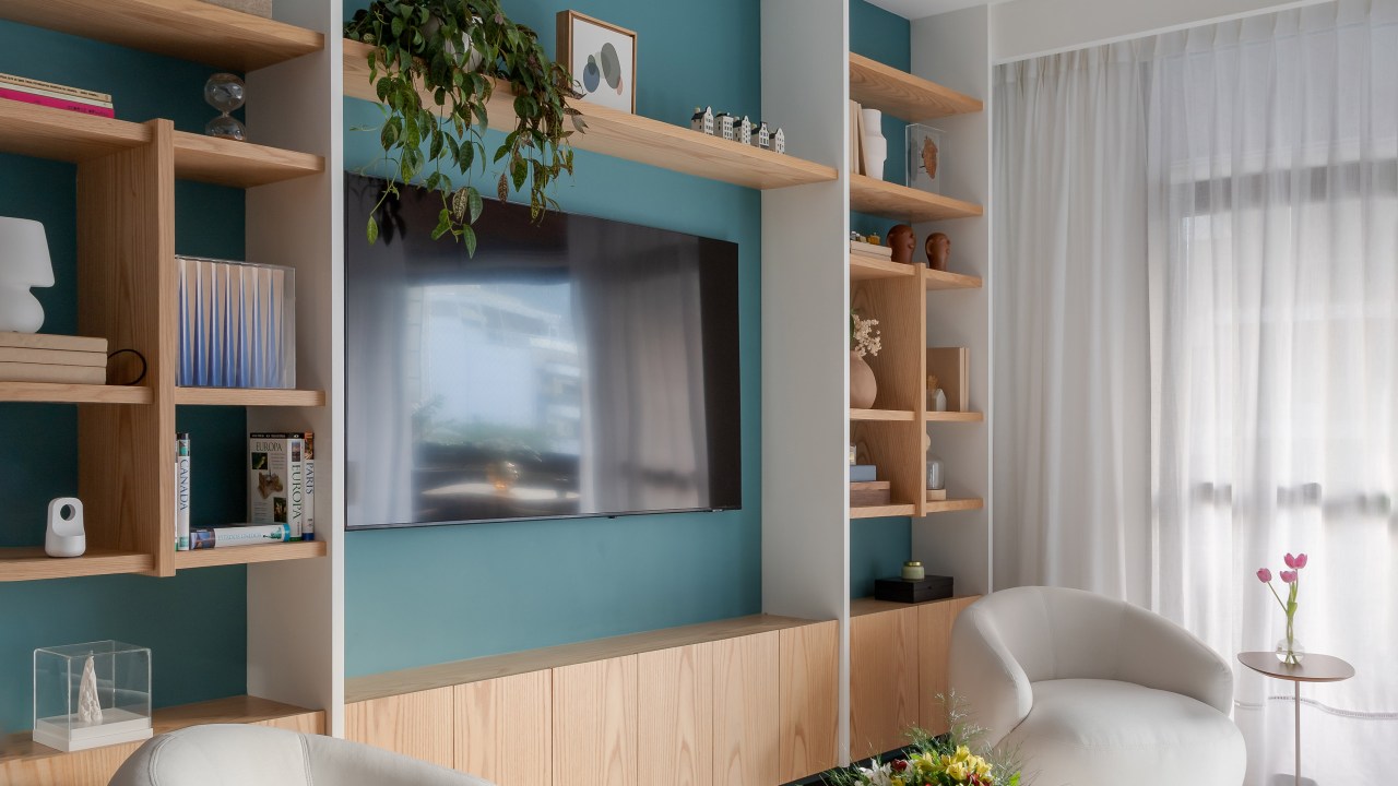 Apartamento de 140 m² ganha charme com paredes azuis e verdes. Projeto de Maia Romeiro Arquitetura. Na foto, sala de estar com parede azul e estante vazada.