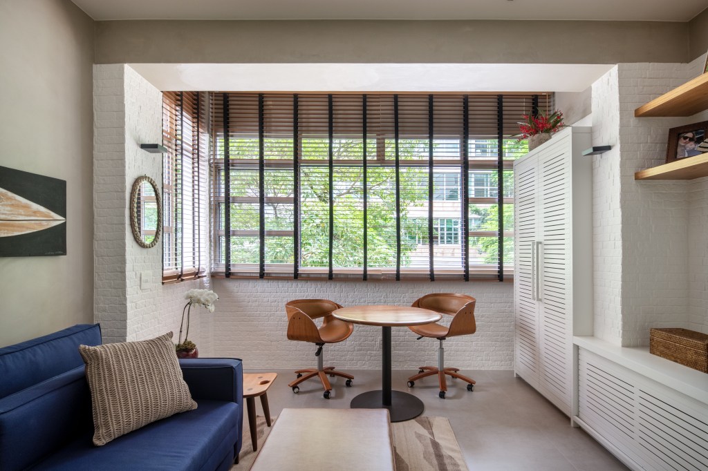 Apartamento carioca de 90 m² tem décor modernista inspirado em Brasília. Projeto de Studio 021 Arquitetura. Na foto, sala com parede de tijolinho e persianas.