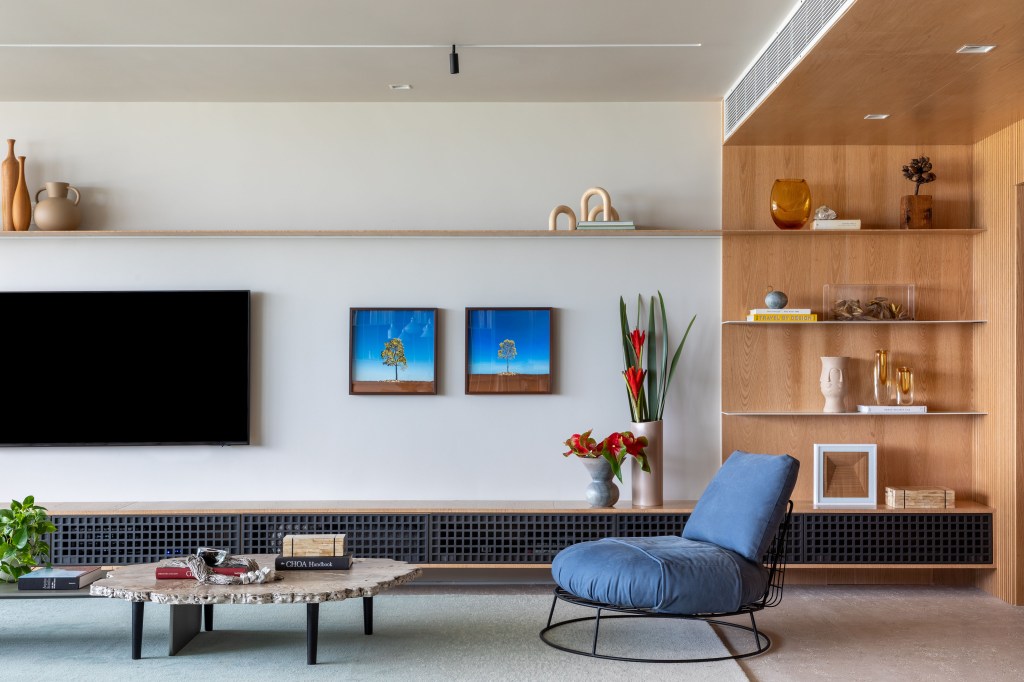 Apartamento com vista para praia ganha espaço de coworking na sala. Projeto de Up3 Arquitetura. Na foto, sala de estar com aparador, tv e quadros.