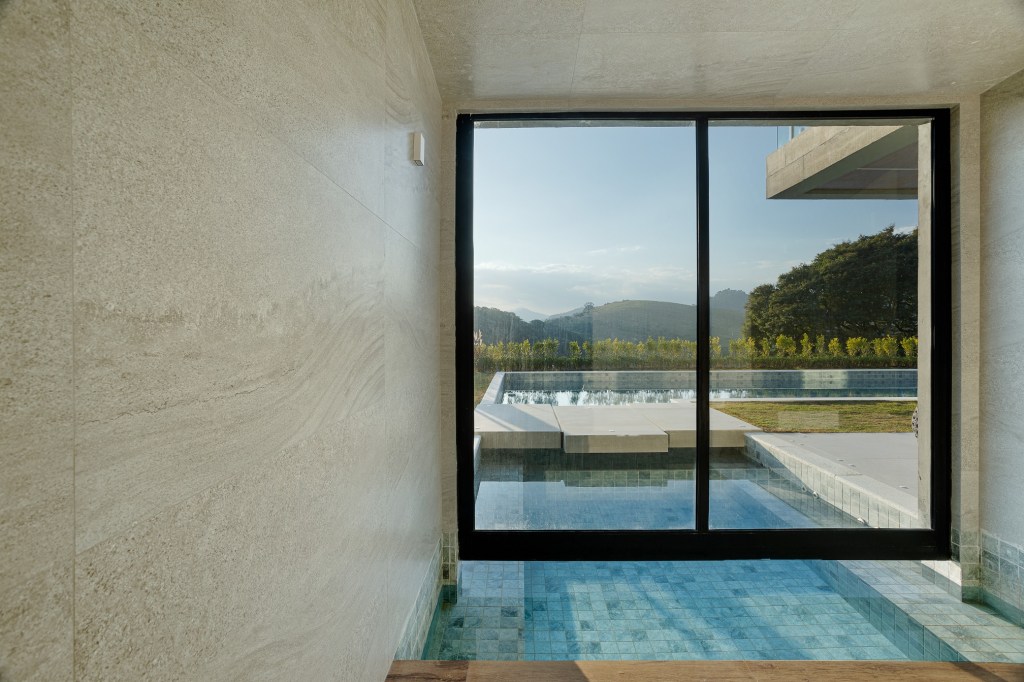 Casa de 1200 m² na serra tem clima de clube de férias. Projeto de Rafael Mirza. Na foto, Na foto, piscina, sauna e vista para o jardim.