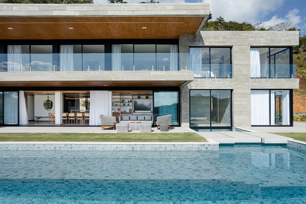 Casa de 1200 m² na serra tem clima de clube de férias. Projeto de Rafael Mirza. Na foto, Na foto, fachada com piscina, varanda e jardim.