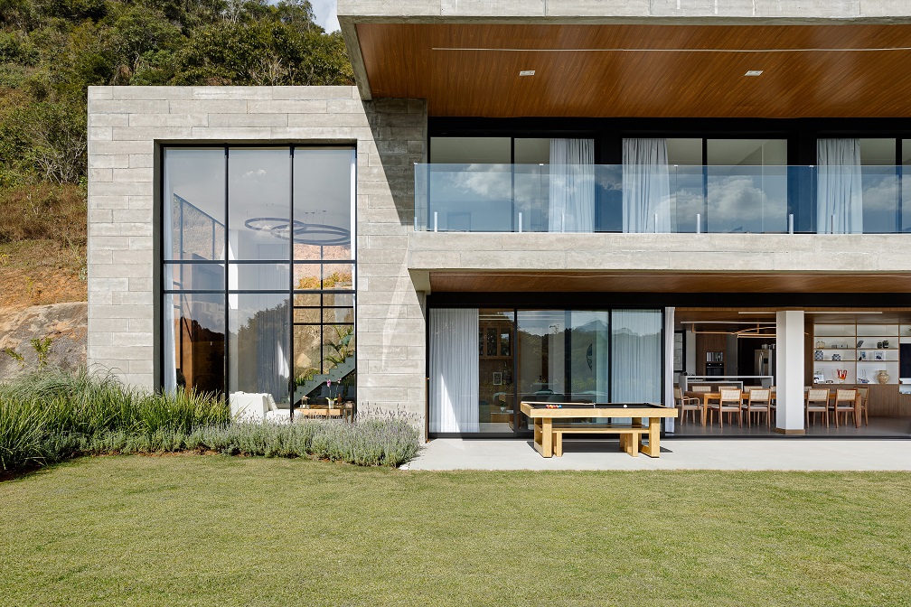 Casa de 1200 m² na serra tem clima de clube de férias. Projeto de Rafael Mirza. Na foto, Na foto, fachada com jardim e varanda.
