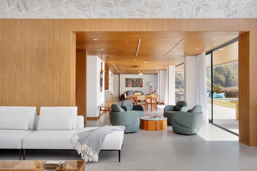 Casa de 1200 m² na serra tem clima de clube de férias. Projeto de Rafael Mirza. Na foto, Na foto, sala de estar e jantar com vista para a piscina.