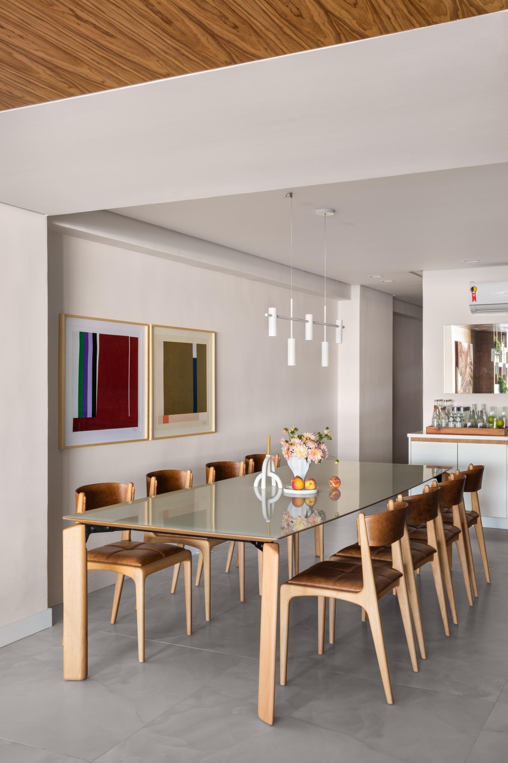 Com vista para o mar, apartamento de 270 m² exalta a arte contemporânea. Projeto de Henrique Ramalho. Na foto, sala de jantar com quadros e cadeira de couro.