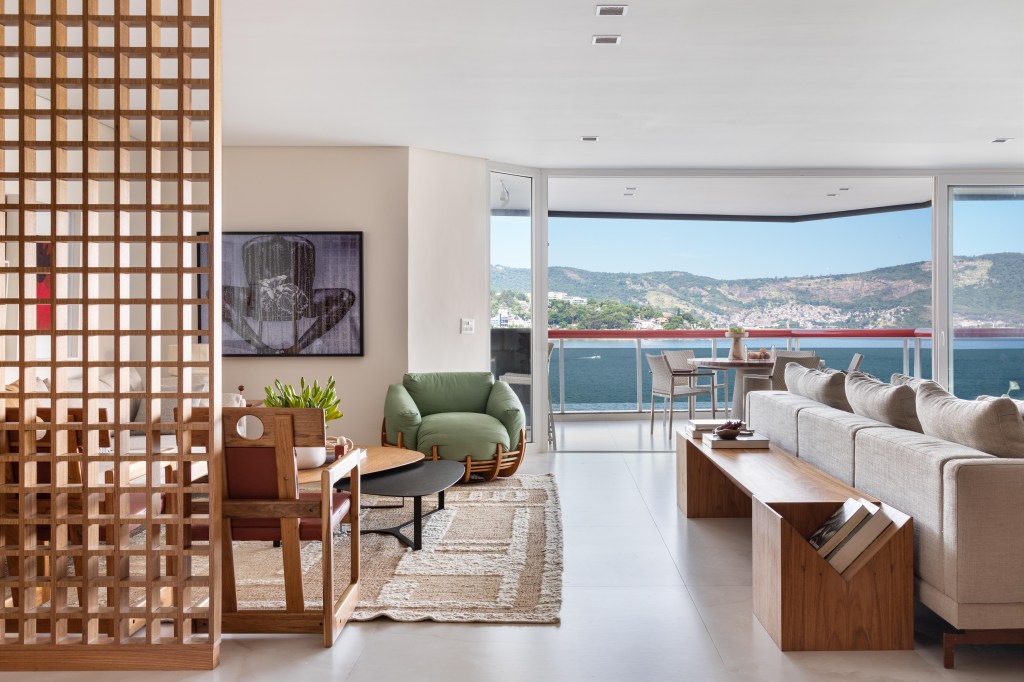 Com vista para o mar, apartamento de 270 m² exalta a arte contemporânea. Projeto de Henrique Ramalho. Na foto, sala de estar com quadros e divisória vazada.