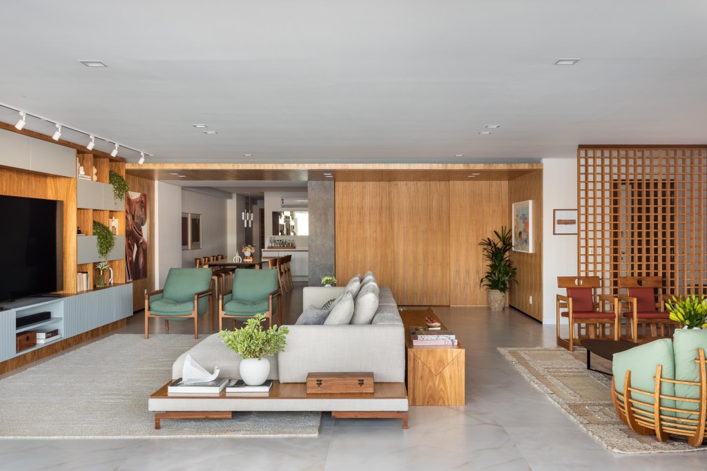 Com vista para o mar, apartamento de 270 m² exalta a arte contemporânea. Projeto de Henrique Ramalho. Na foto, sala de estar e TV com paredes de madeira.