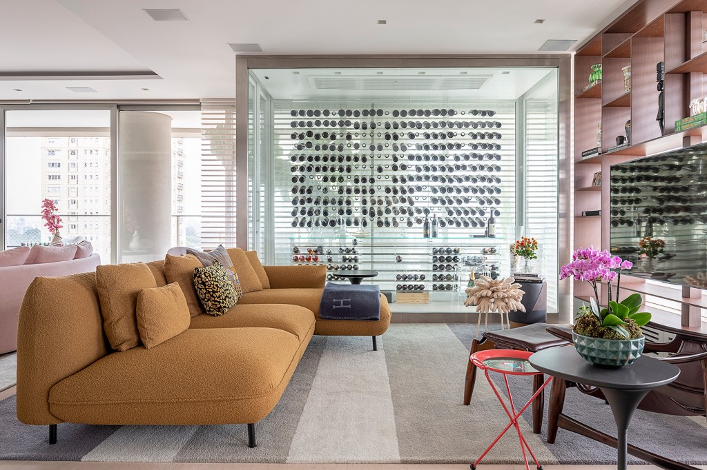 Adega para mil garrafas marca a área social deste apartamento de 632 m². Projeto de Ana Weege. Na foto, sala de estar com adega transparente e tv.