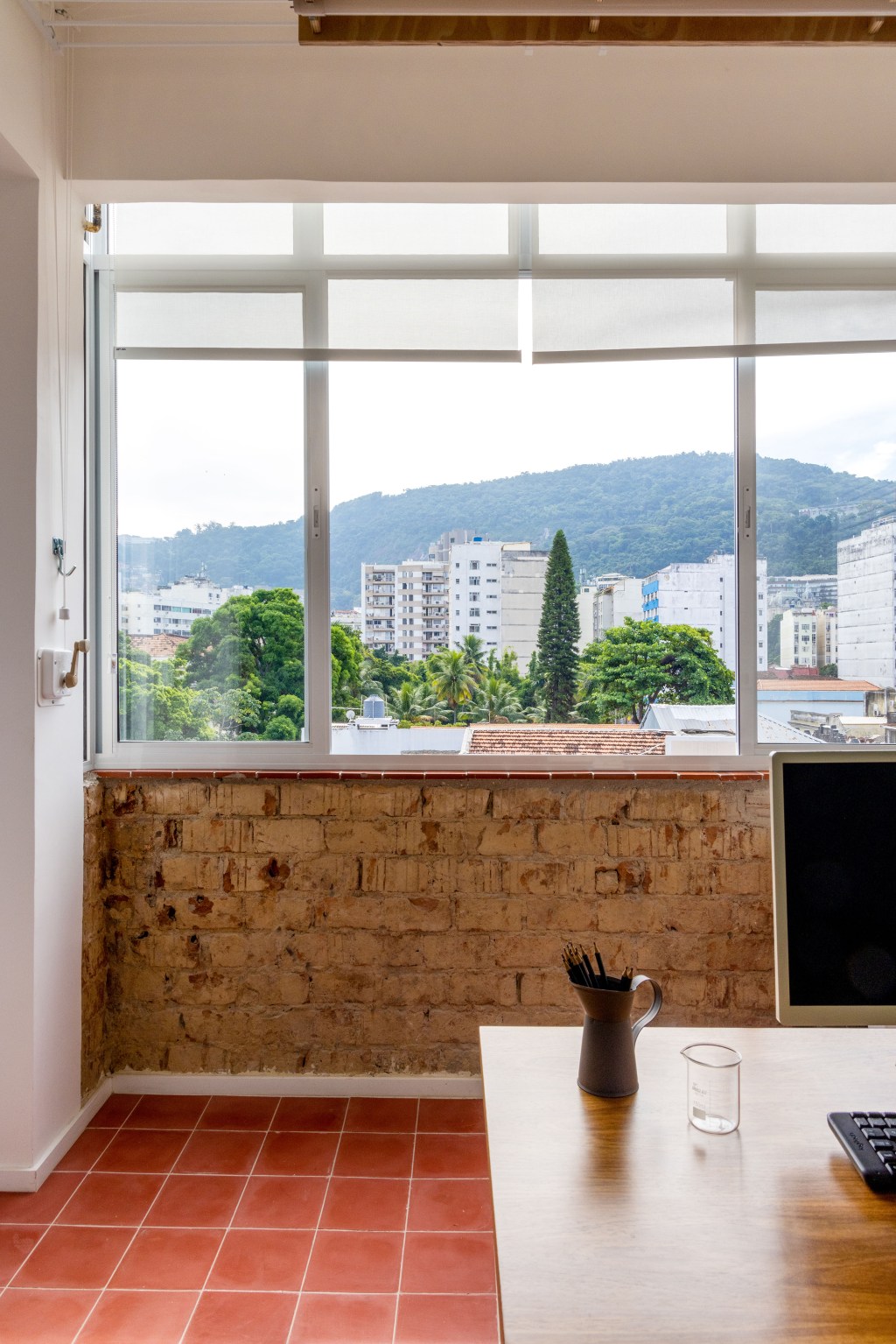 Apê de 90 m² ganha cara de casa com revestimentos charmosos e cores. Projeto Ana Neri. Na foto, home office com parede verde e prateleiras.