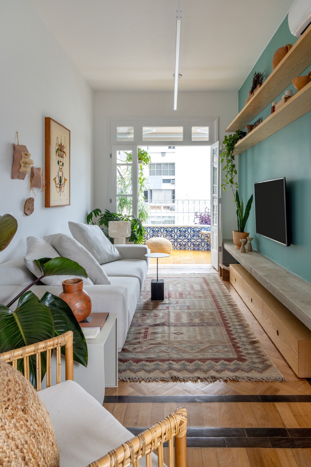 Apê de 90 m² ganha cara de casa com revestimentos charmosos e cores. Projeto Ana Neri. Na foto, sala com parede verde, tapete e quadros.