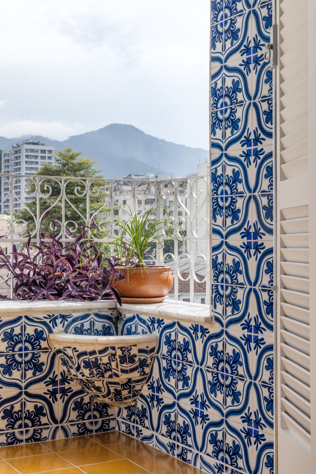 Apê de 90 m² ganha cara de casa com revestimentos charmosos e cores. Projeto Ana Neri. Na foto, varanda com azulejo português e vasos de plantas.