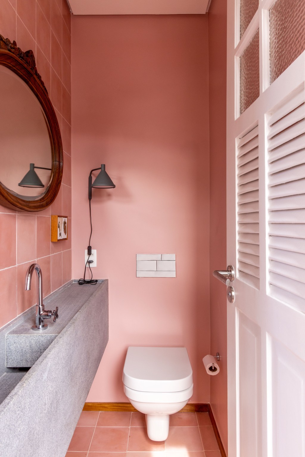 Apê de 90 m² ganha cara de casa com revestimentos charmosos e cores. Projeto Ana Neri. Na foto, lavabo com parede rosa e espelho redondo.