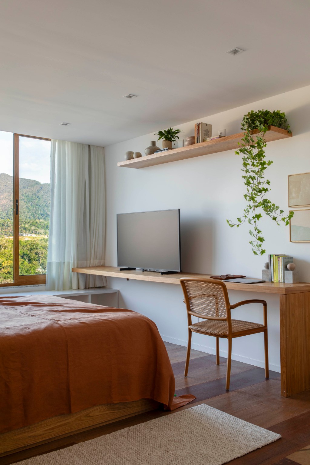 Casa de campo de 800 m² em Petrópolis ganha décor com cara de montanha. Projeto de João Panaggio. Na foto, quarto de casal com tv e vista para a natureza.