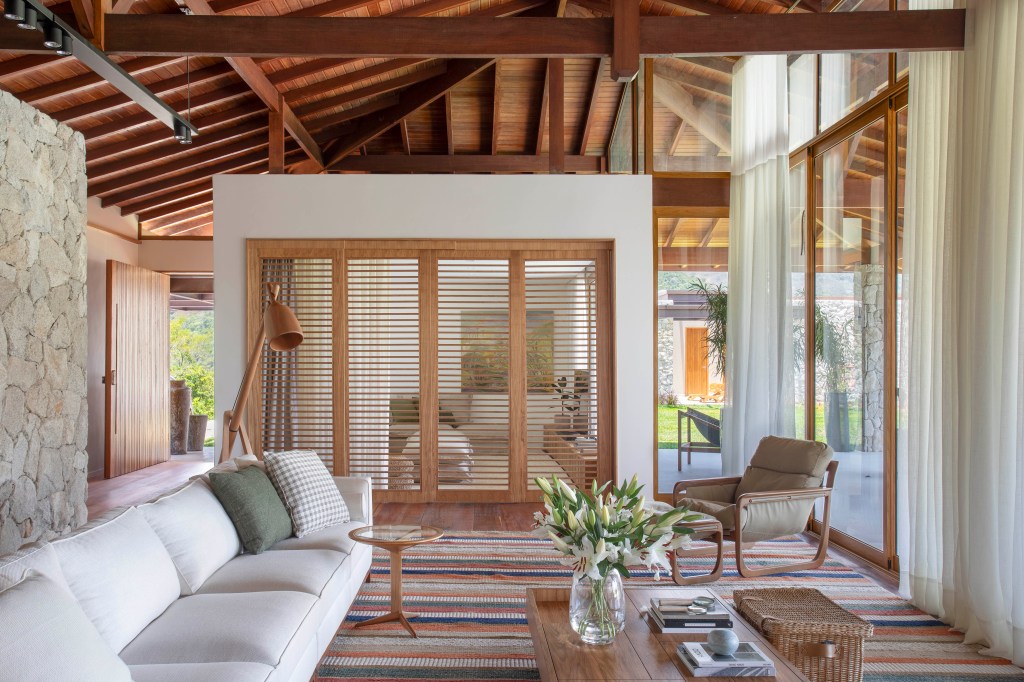 Casa de campo de 800 m² em Petrópolis ganha décor com cara de montanha. Projeto de João Panaggio. Na foto, sala com porta de madeira e poltrona.