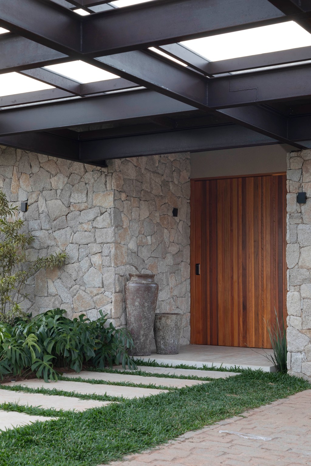 Casa de campo de 800 m² em Petrópolis ganha décor com cara de montanha. Projeto de João Panaggio. Na foto, fachada com pergolado e parede de pedra.