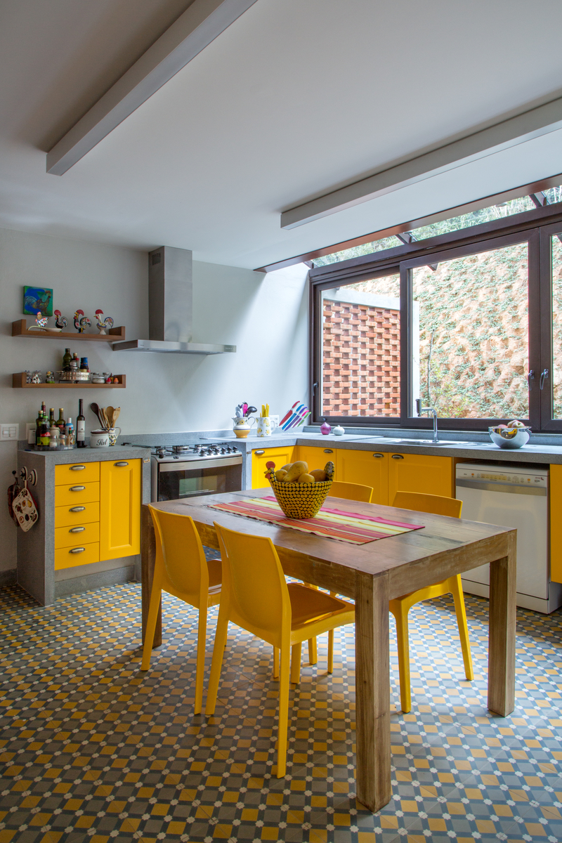 Casa na montanha possui vista espetacular para a Serra das Araras. Projeto de Andrea Chicharo. Na foto, cozinha com piso de ladrilho hidráulico e móveis amarelos.