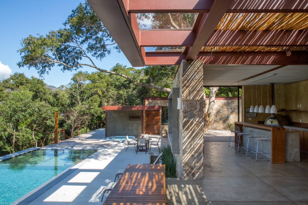 Casa na montanha possui vista espetacular para a Serra das Araras. Projeto de Andrea Chicharo. Na foto, área de lazer com piscina e jardim. Pergolado de bambu.