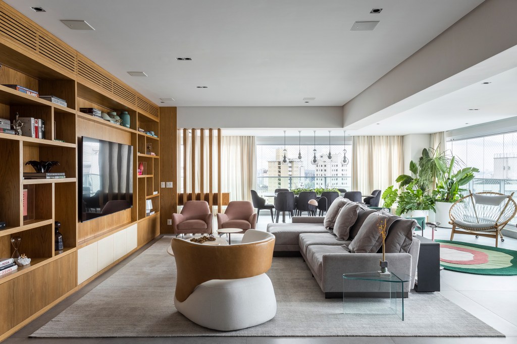 Contemporaneidade, integração e tons neutros marcam apartamento de 311 m². Projeto BZP Arquitetura. Na foto, sala de TV com marcenaria planejada e sofá cinza.