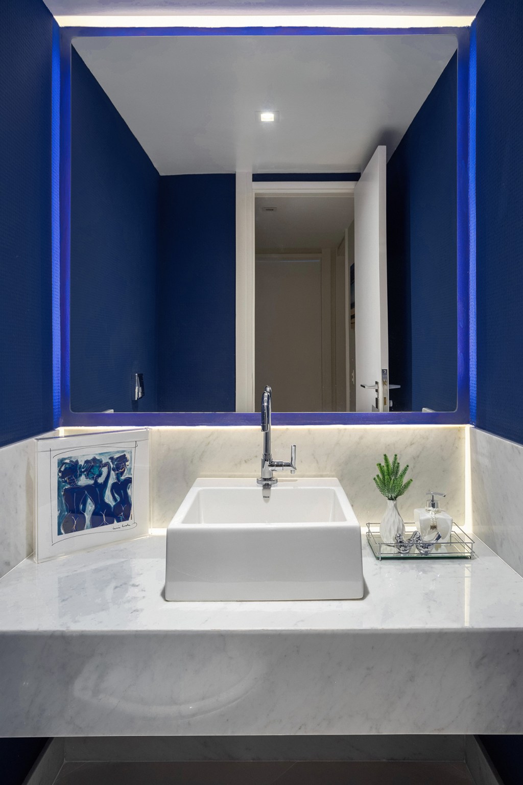 Cores vivas marcam décor deste apartamento de 300 m² com pé-direito duplo. Projeto de Ana Cano. Na foto, lavabo com parede azul e iluminação indireta.