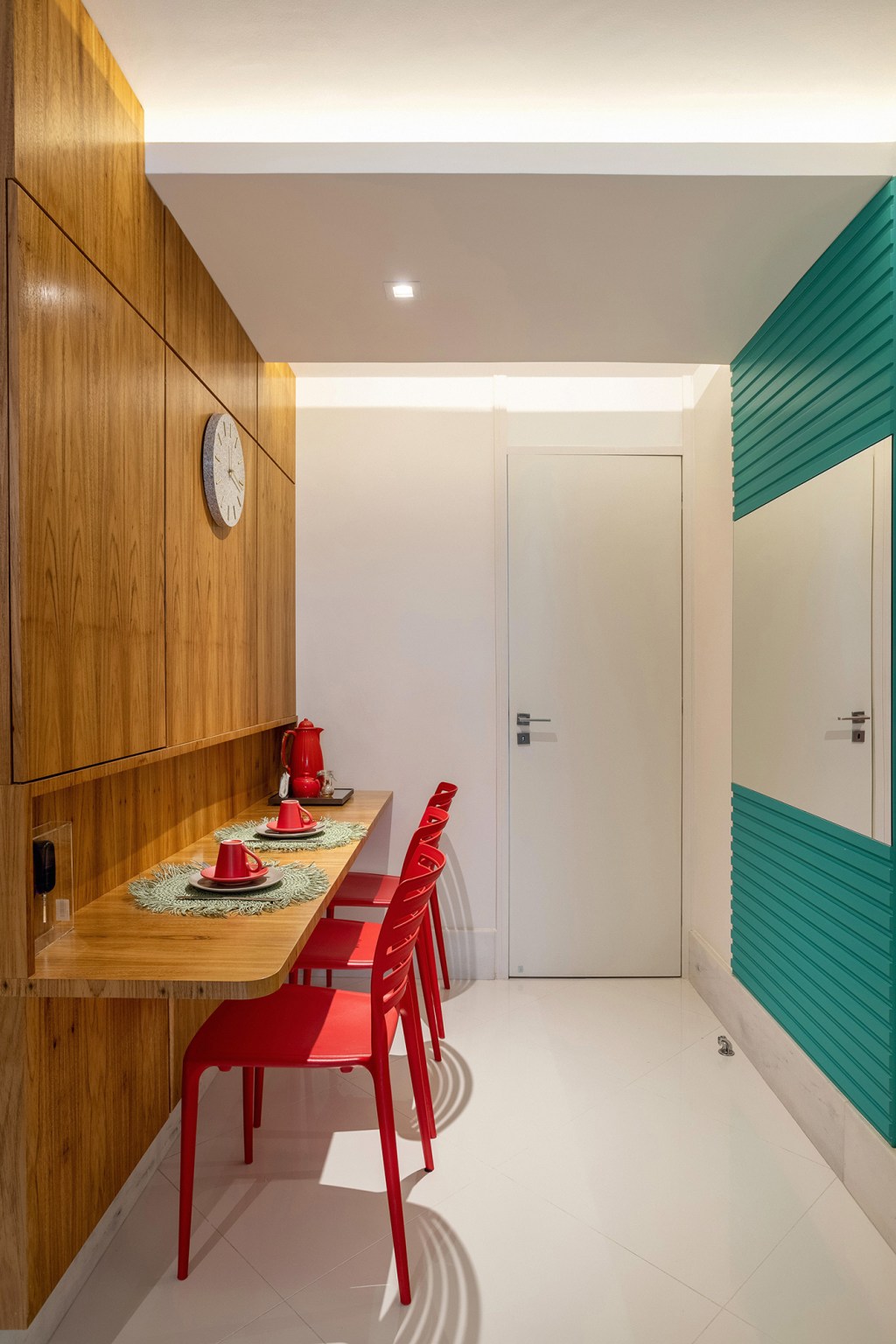 Cores vivas marcam décor deste apartamento de 300 m² com pé-direito duplo. Projeto de Ana Cano. Na foto, copa com cadeira vermelha e parede verde.