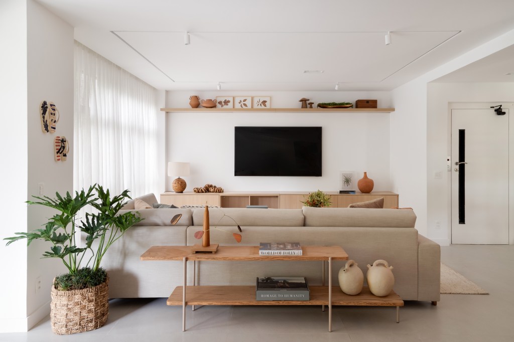Décor neutro, tons terrosos e verde oliva marcam este apê de 230 m². Projeto de Paula Muller. Na foto, sala de estar com TV, sofá e aparador.