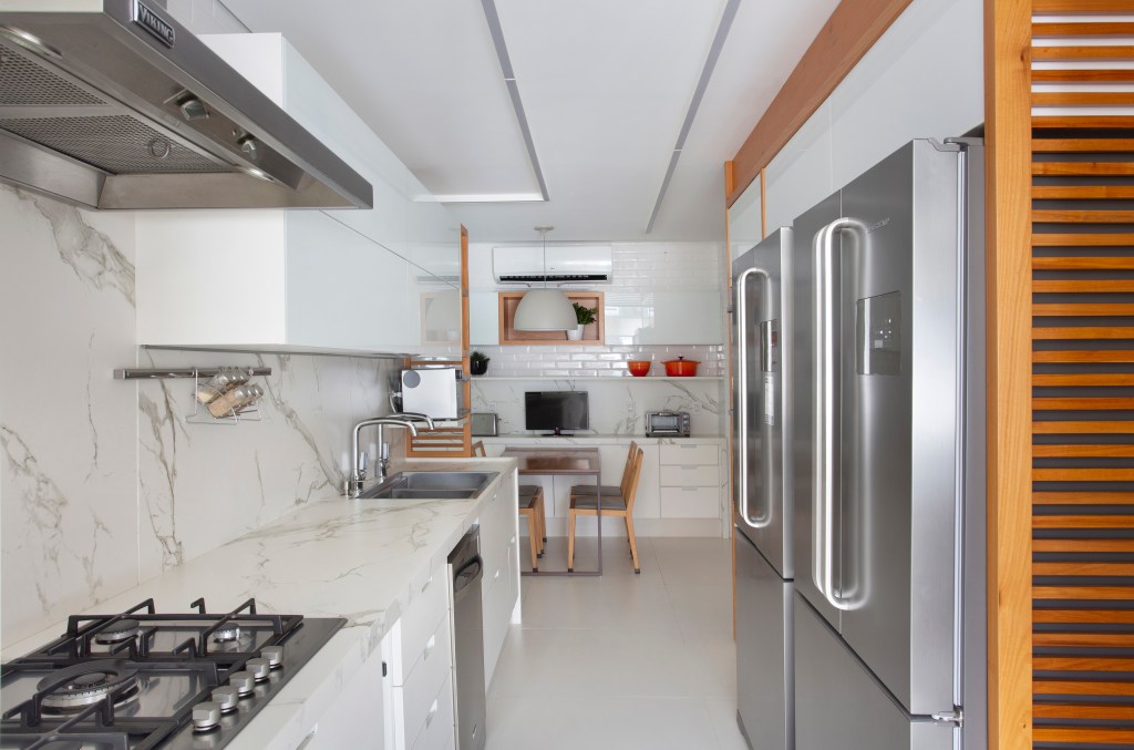 O mar do Leblon é o pano de fundo deste apartamento de 280 m². Projeto de Studio 021 Arquitetura. Na foto, cozinha com dekton marmorizado e área de refeições.