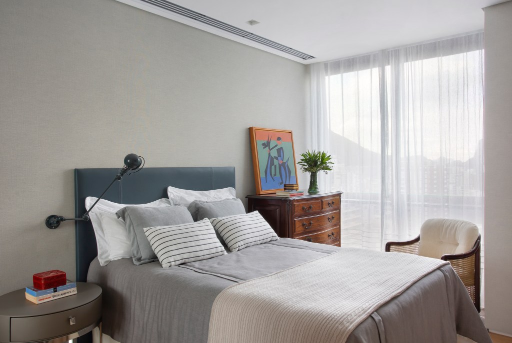 O mar do Leblon é o pano de fundo deste apartamento de 280 m². Projeto de Studio 021 Arquitetura. Na foto, quarto de casal com cama com cabeceira azul e quadro.