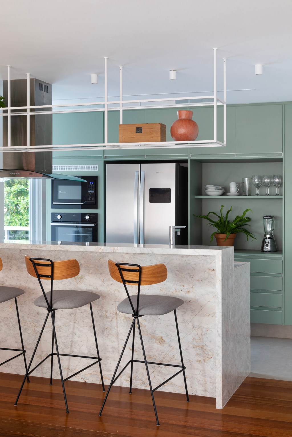 Paredes brancas, piso de madeira e armários verdes marcam apê de 280 m². Projeto Beta Arquitetura. Na foto, cozinha americana com armários verdes.