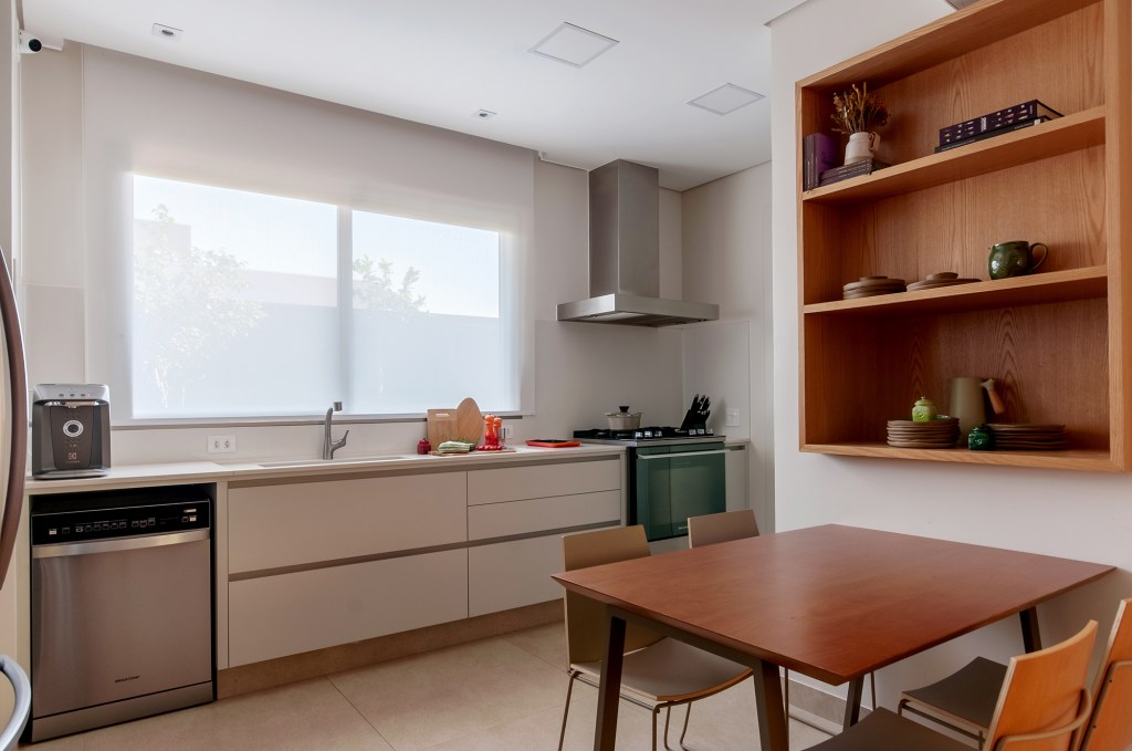 Construída do zero, casa une ambientes integrados e design nacional. Projeto de Paiva e Passarini Arquitetura. Na foto, cozinha com copa e estante.