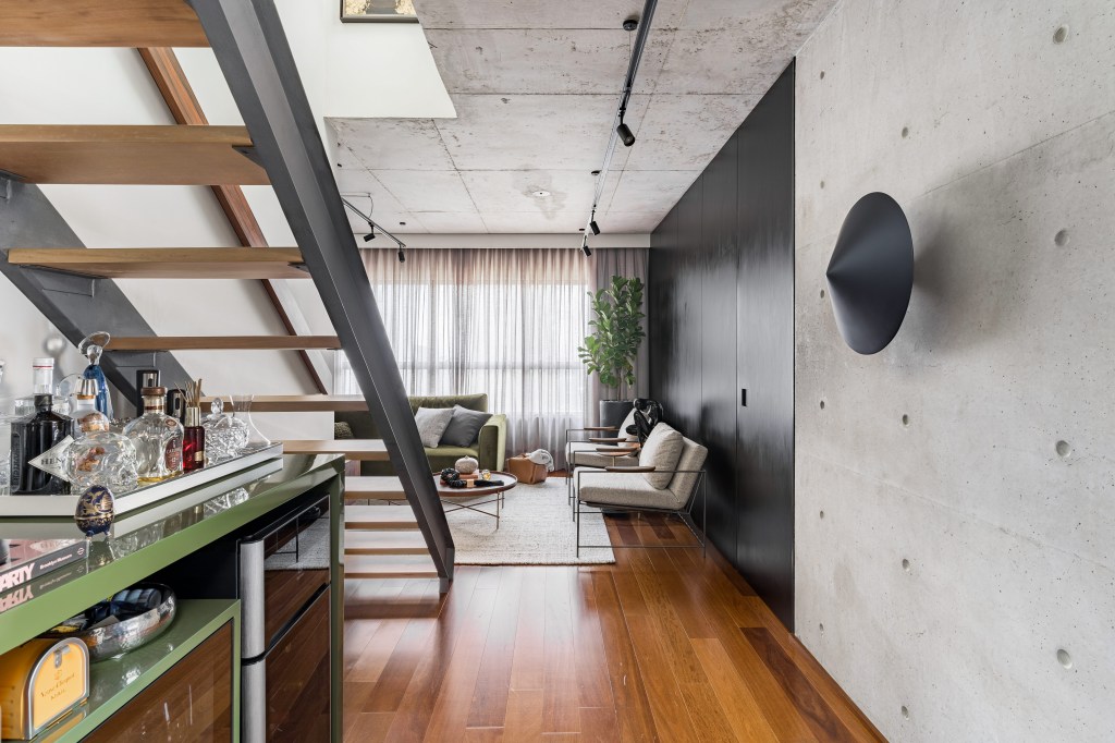 Gabriela Prado assina apê industrial de 140 m² com jardim de cactos. Na foto, sala com parede preta e escada vazada.