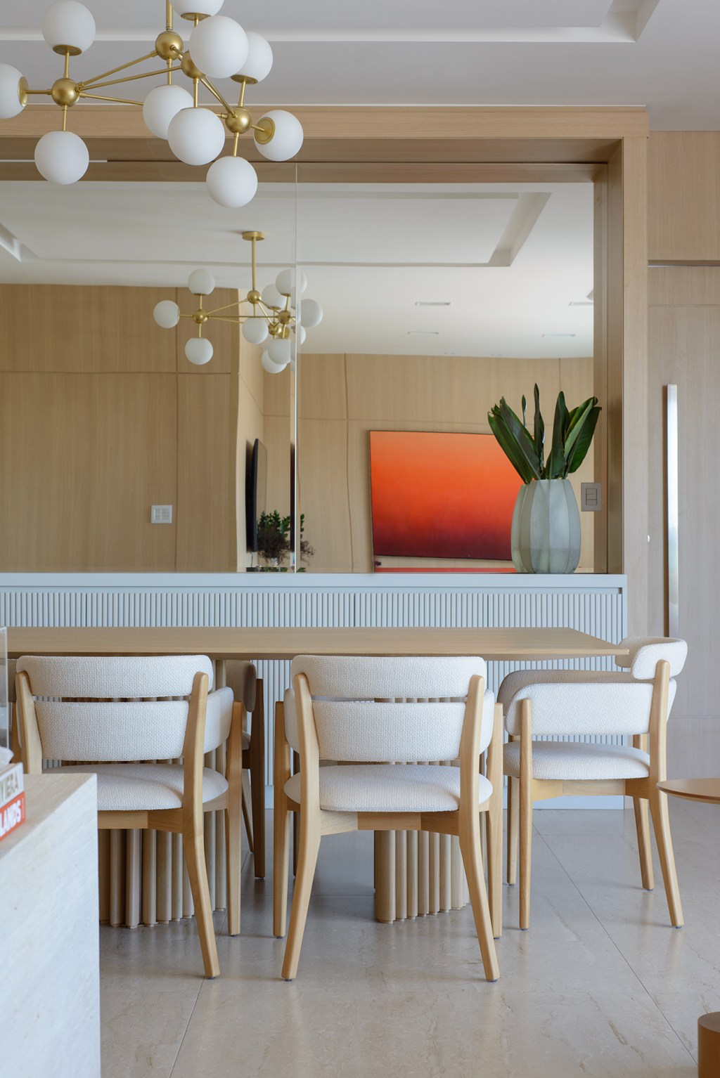Móveis contemporâneos e paredes amadeiradas marcam este apê de 138 m². Projeto de Leticia Nanetti. Na foto, sala de jantar com espelho e aparador ripado.