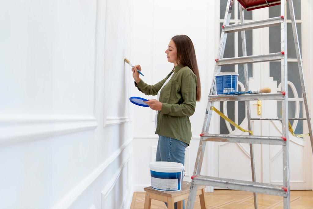 Mulher retocando pintura parede
