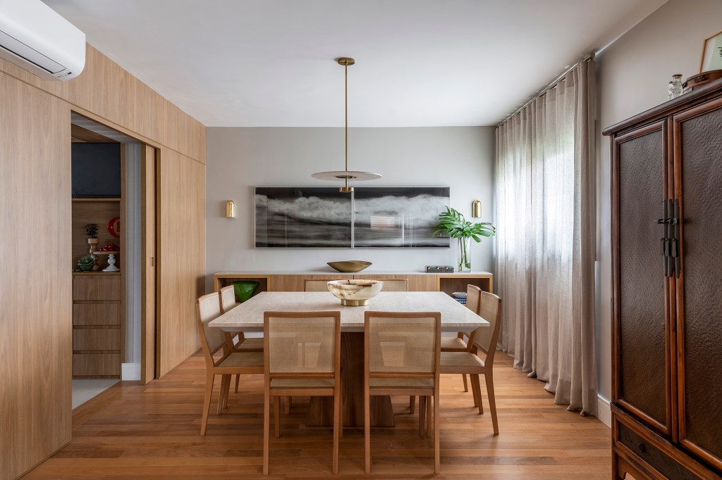 Paola Ribeiro assina apartamento de 196 m² com alma carioca em SP. Projeto de Paola Ribeiro, Na foto, sala de jantar com cadeira de palhinha e quadro.