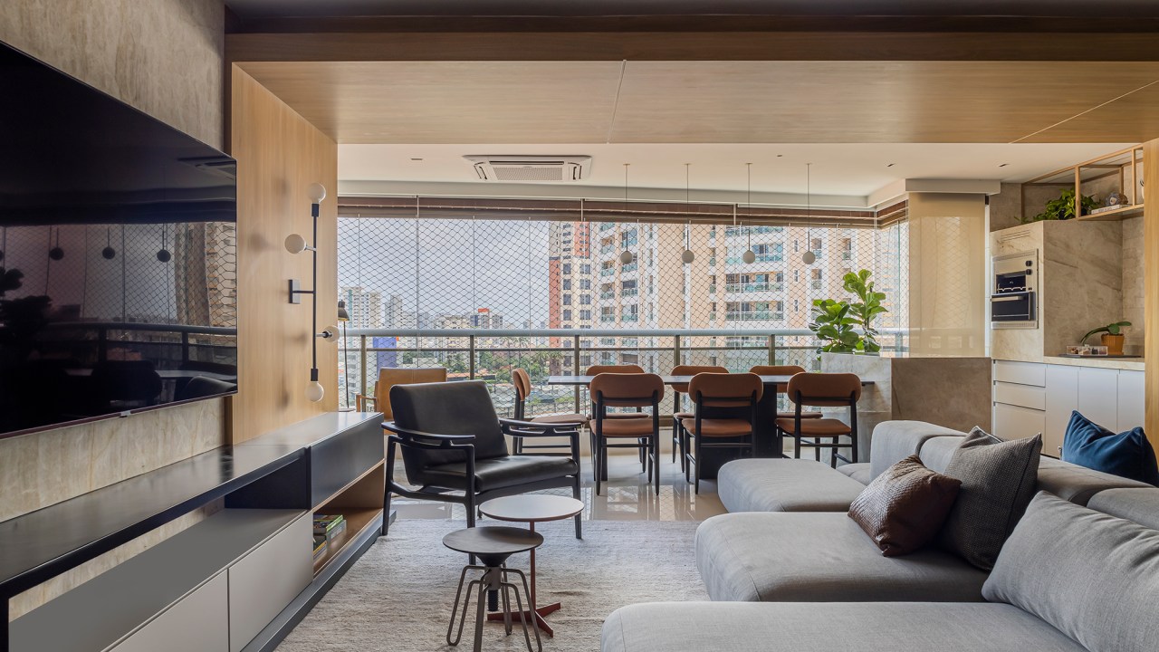 Romário Rodrigues cria projeto contemporâneo em apê de 220 m² no Ceará. Na foto, sala integrada à varanda com tv, churrasqueira e sofás.