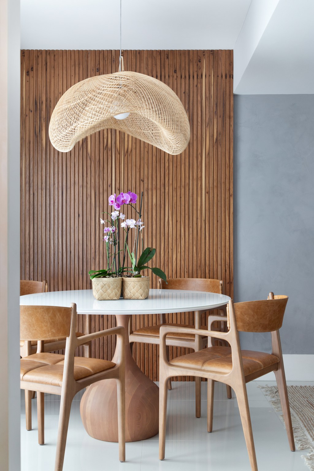 Sem quebra-quebra, apê de 130 m² no Rio ganha décor cozy e minimalista. Projeto Travessa Arquitetura. Na foto, sala de jantar com mesa redonda e parede ripada.