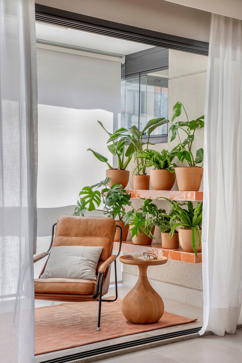 Sem quebra-quebra, apê de 92 m² ganha projeto afetivo e com biofilia. Projeto de Fabiano Ravaglia. Na foto, varanda com vasos de plantas e poltrona.