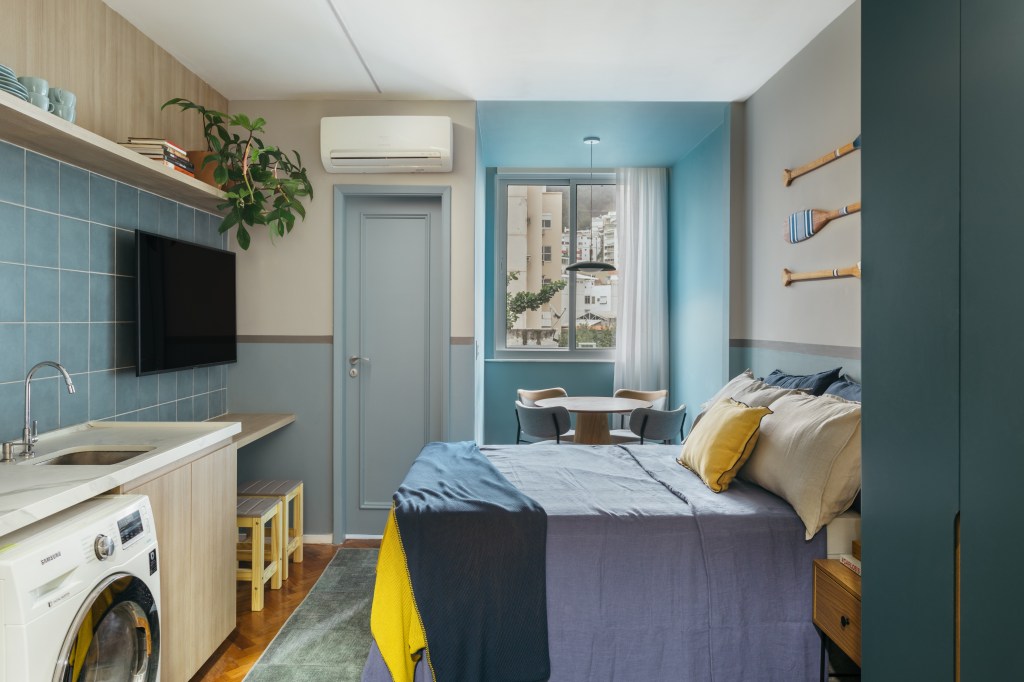 Apê de 25 m² ganha décor praiana com parede de cerâmica azul. Projeto de Rodolfo Consoli. Na foto, sala, cozinha, lavanderia e tv.