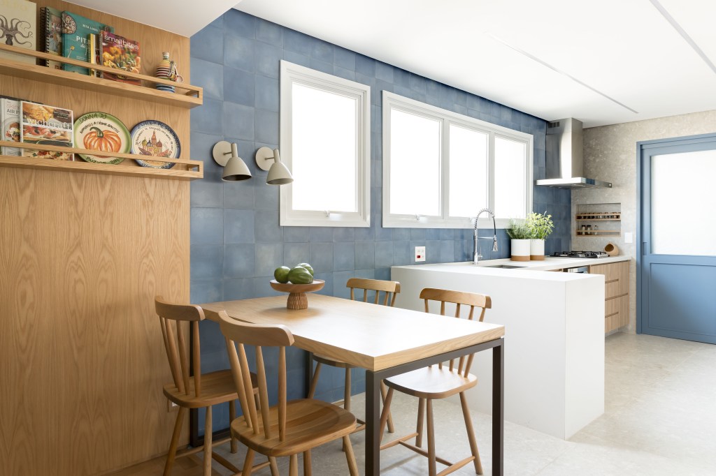Apê eclético: minimalismo, shabby chic e industrial se mesclam em 180 m². Projeto Studio Lak. Na foto, cozinha com parede azul, copa e mesa de refeições.