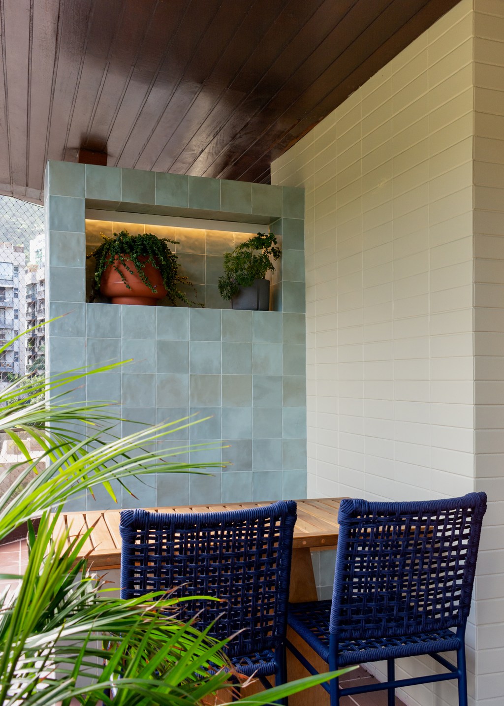 A madeira é a protagonista deste apartamento de 117 m² na Gávea. Projeto de Mariana Monnerat, Na foto, varanda com cadeira azul e vasos.