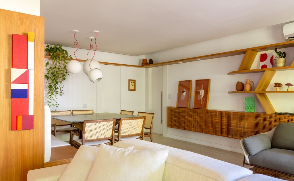 A madeira é a protagonista deste apartamento de 117 m² na Gávea. Projeto de Mariana Monnerat, Na foto, sala de jantar com aparador e quadros.