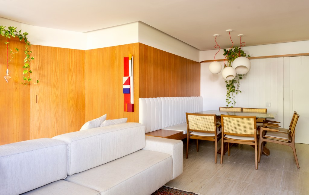 A madeira é a protagonista deste apartamento de 117 m² na Gávea. Projeto de Mariana Monnerat, Na foto, sala de jantar com banco e sofá ilha.