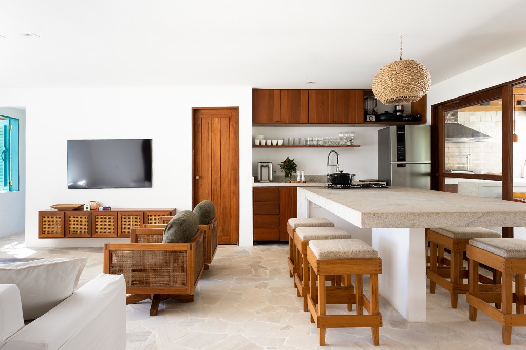 Refúgio tropical: casa em Trancoso ganha quarto de hóspedes na edícula. Projeto Conrado Ceravolo. Na foto, sala com poltronas e sofá. Cozinha integrada.