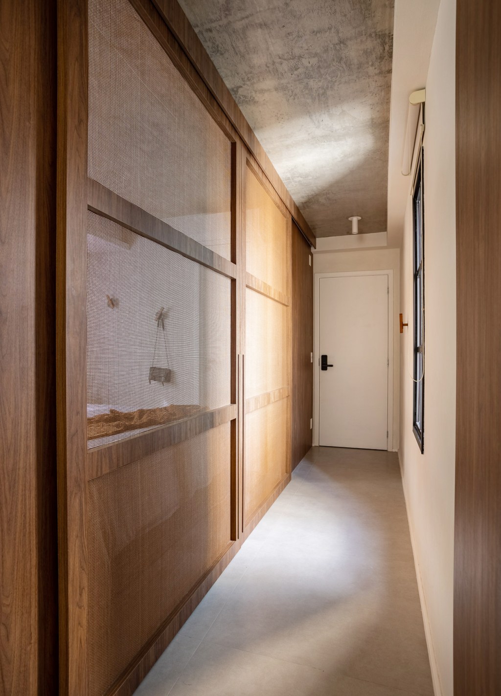 Wabi-sabi norteia a decoração de apartamento de apenas 48 m². Projeto de Carolina Gava. Na foto. corredor com porta telada.