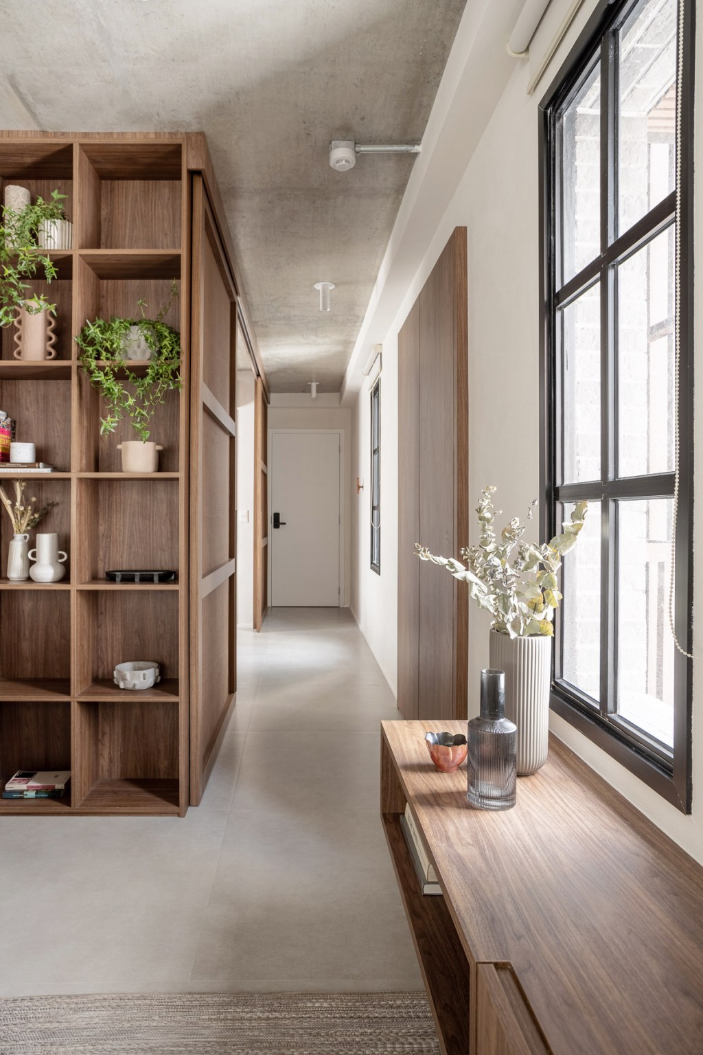 Wabi-sabi norteia a decoração de apartamento de apenas 48 m². Projeto de Carolina Gava. Na foto. corredor com banco e estante.