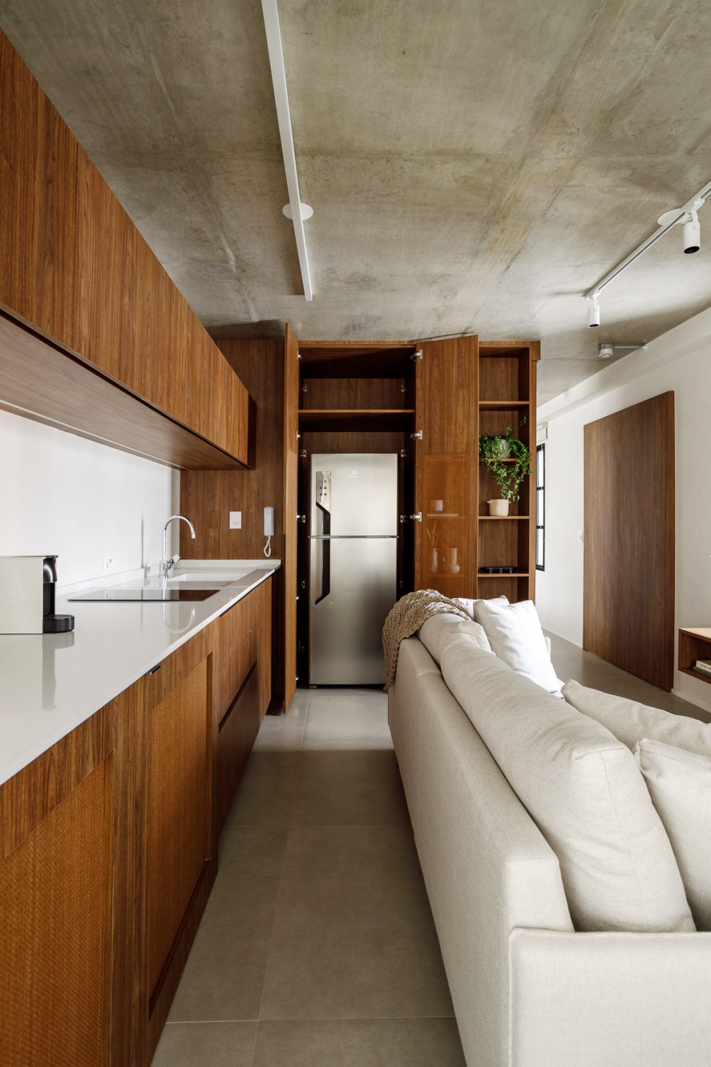 Wabi-sabi norteia a decoração de apartamento de apenas 48 m². Projeto de Carolina Gava. Na foto. sala com sofá branco e cozinha integrada.